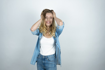 blonde girl holding hands near head looks surprised white isolated background