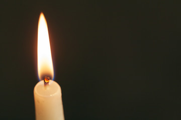 A single burning candle isolated with black background