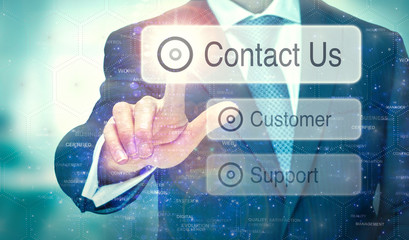 A businessman selecting a button on a futuristic display with a Contact Us concept written on it.