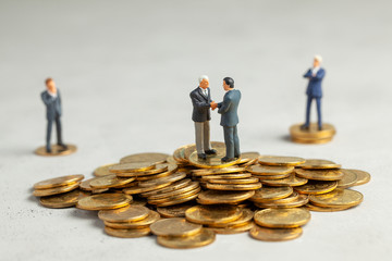 Businessmen shake hands as a symbol of a successful profitable transaction. Businessmen on a stack of gold coins as a symbol of success or successful investments