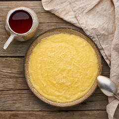 porridge polenta with cup tea, dark wood background, top view