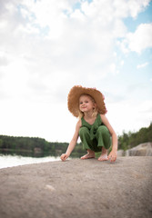 Little cute girl in stylish clothes on a background of rocks. Summer portrait of a little girl in a hat and cotton clothes for a magazine or advertisement
