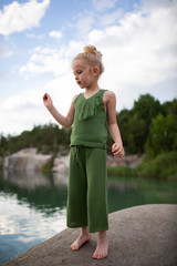 Little cute girl in stylish clothes on a background of rocks. Summer portrait of a little girl cotton clothes for a magazine or advertisement