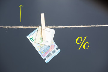 Dinero, billetes de Euro colgados por pinzas en una cuerda como si fueran ropa estendida para ser...