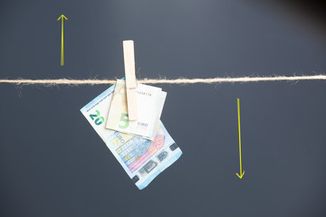 Dinero, billetes de Euro colgados por pinzas en una cuerda como si fueran ropa estendida para ser...