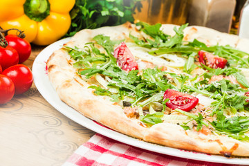 Homemade italian pizza, fresh cherry tomatoes and basil, arugula served on wooden board
