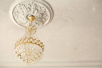 Crystal chandelier on the ceiling with stucco. Copy space