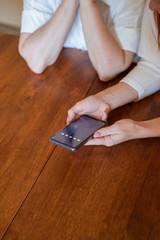 Two women vote in a smartphone while sitting at the table. The hands of the mother and daughter holding the phone and arranging the rating, a bad score. Experience . Phone closeup