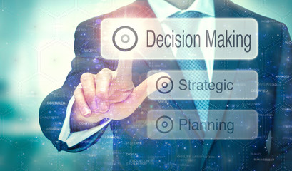A businessman selecting a button on a futuristic display with a Decision Making concept written on...