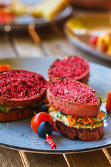 Vegan sandwiches for breakfast with beetroot bread, hummus and vegetables.