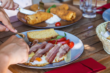 Fried eggs with bacon, cheese and bread for breakfast in a European cafe.