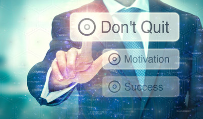 Fototapeta na wymiar A businessman selecting a button on a futuristic display with a Don't Quit concept written on it.