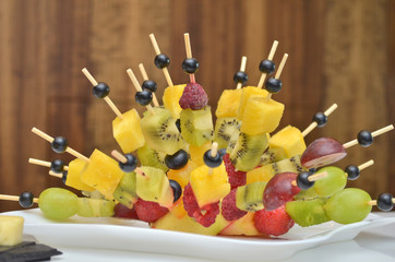 Fruity canapes in the form of a hedgehog at a banquet on the table on a wooden background closeup