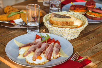 Montenegro breakfast in the restaurant. Fried eggs with bacon, pancakes and sandwiches.