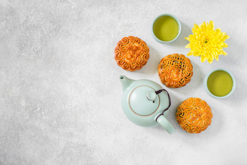 Mooncakes, blue teapot, yellow chrysanthemum flowers and cup of green tea. Chinese mid-autumn festival food.