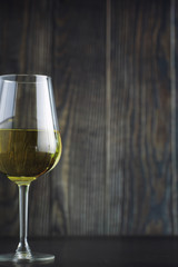 Transparent bottle of white dry wine on the table. White wine glass on a wooden background.