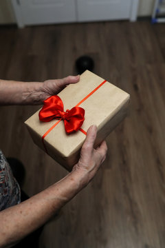 gift box with red bow in grandmother hands