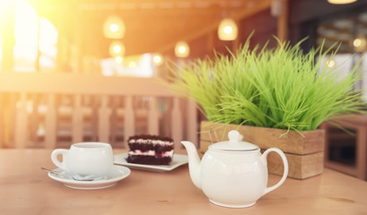 Kettle with a drink and dessert in a street cafe. Tea in the kettle cup on the table. Breakfast with tea and cakes at the cafe.