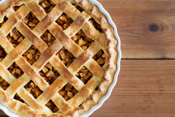 food, culinary and baking concept - close up of apple pie in mold on wooden table