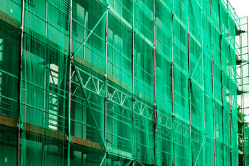 Fototapeta na wymiar The building is being repaired and it was fenced from the street with a green grid.