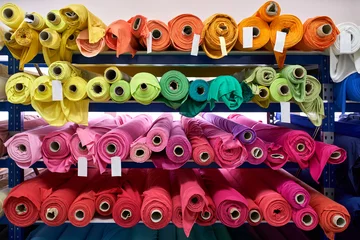 Poster Fabric warehouse with many multicolored textile rolls © Andriy Bezuglov