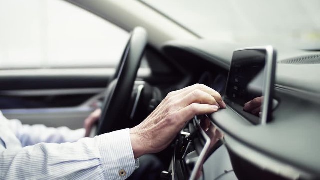 Midsection of man driver sitting in car, setting radio or navigation.