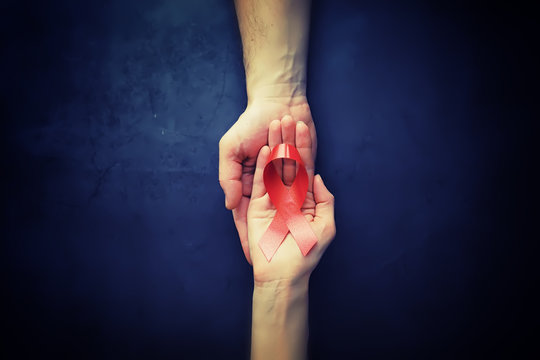 Symbol of human immunodeficiency virus disease. Red ribbon. A helping hand and support.