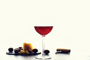 A glass of red dry wine on the table. Dark bottle and glass of wine.