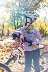 Cute little girl with a bicycle in the autumn forest