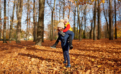 childhood, season and people concept - happy children having fun at autumn park