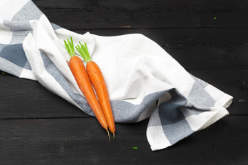 Bunch of fresh carrots with green leaves on wooden table