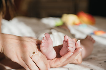 maternal care. mother and child. mother's love mothers Day. newborn. baby feet in mom's hands close up