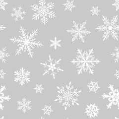 Fototapeta na wymiar Christmas seamless pattern of complex big and small snowflakes in white colors on gray background