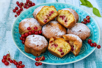 Homemade muffins with berries, sprinkled with powdered sugar, arranged on a blue wooden table, rustic style
