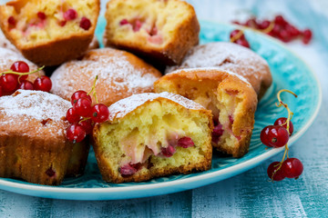 Homemade muffins with berries, sprinkled with powdered sugar, arranged on a blue wooden table, rustic style