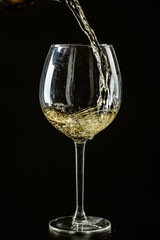White wine being poured in a wine glass on a dark background