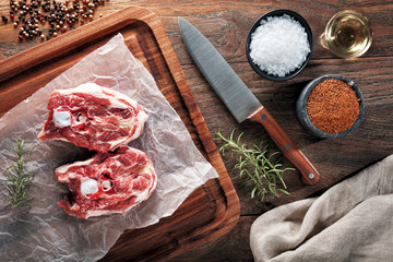 Raw lamb neck meat on white cooking paper and wooden cutting table.