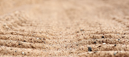 Background the tread marks of the machine on sand close up. Background in blur.