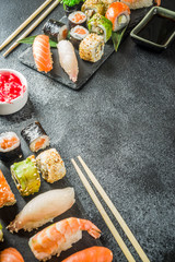 Assorted sushi set on stone or concrete background.  Japanese classic sushi, sushi nigiri. rolls, soy sauce, ginger, chopsticks. Top view. copy space