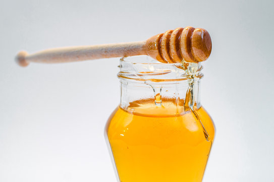 Close up of wooden honey spoon on class jar full of honey