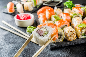Assorted sushi set on stone or concrete background.  Japanese classic sushi, sushi nigiri. rolls, soy sauce, ginger, chopsticks. Top view. copy space
