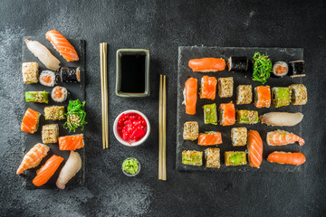 Assorted sushi set on stone or concrete background.  Japanese classic sushi, sushi nigiri. rolls, soy sauce, ginger, chopsticks. Top view. copy space