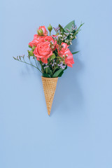 Flat lay Ice Cream Cones with colorful bouquet on blue background, copy space
