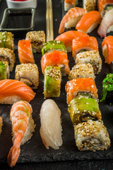 Assorted sushi set on stone or concrete background.  Japanese classic sushi, sushi nigiri. rolls, soy sauce, ginger, chopsticks. Top view. copy space