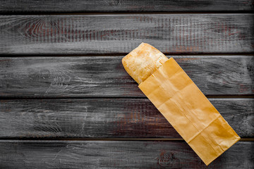 Fresh baguette and paper bag for bakery on wooden background top view mock-up
