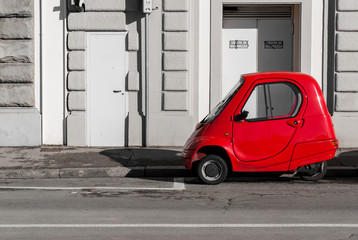 Una buffa macchina rossa, elettrica e a tre ruote, in centro a Firenze in una giornata di sole