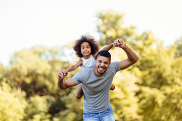 Portrait of young father carrying his daughter on his back