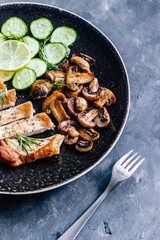 Dish of roasted meat, champignon mushrooms,cucumber and rosemary. Close up. Dark styled photo.