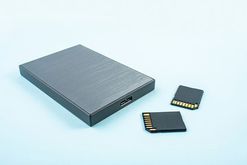Mobile hard drive and memory card on blue background
