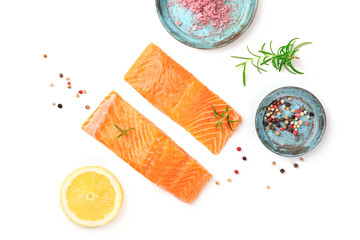 Two slices of fresh raw salmon with Himalayan salt, pepper, rosemary, and lemon, shot from above on...